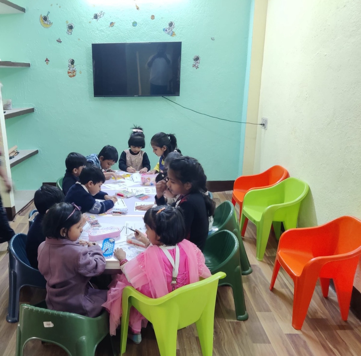 Children working at a table beneath a wall-mounted screen in the audio-visual room