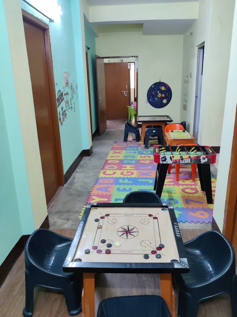 Indoor games area with a carrom board, table football and an alphabet floor mat