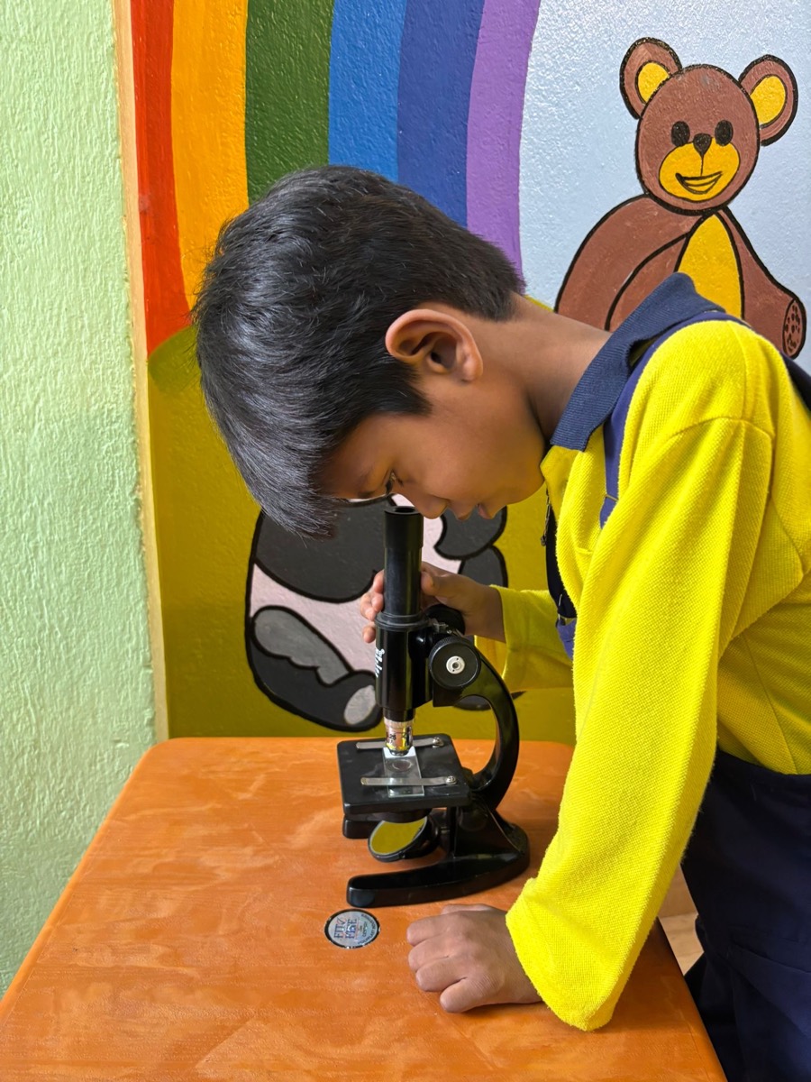 A child looking into a microscope at the activity lab table