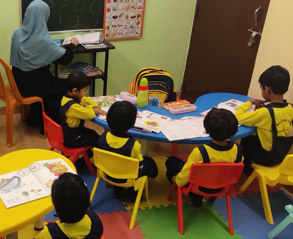 A teacher working with a small group of children around a table