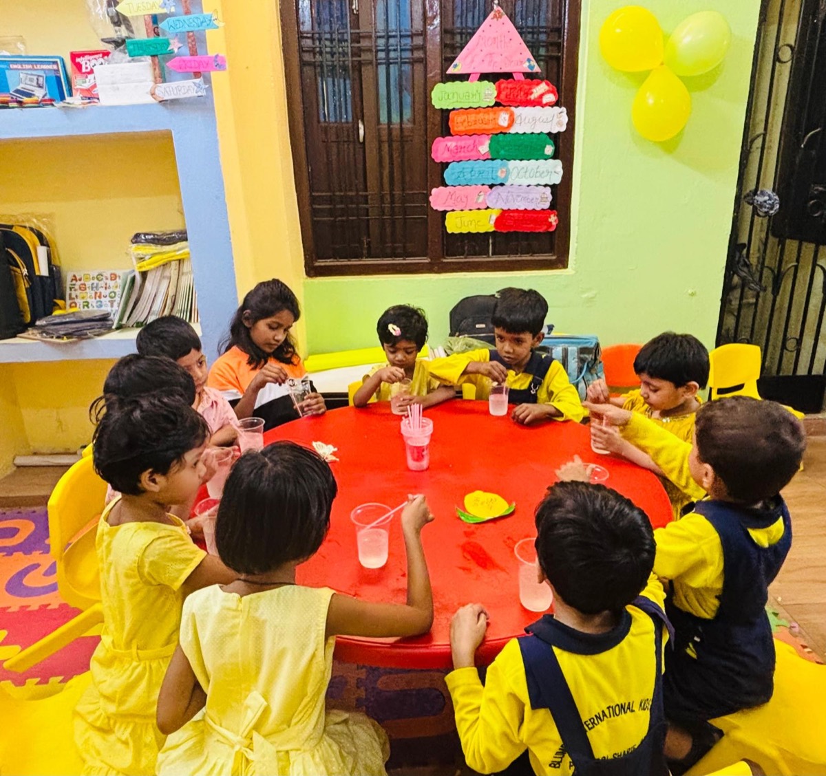Children dressed in yellow sharing drinks around a table on Yellow Day
