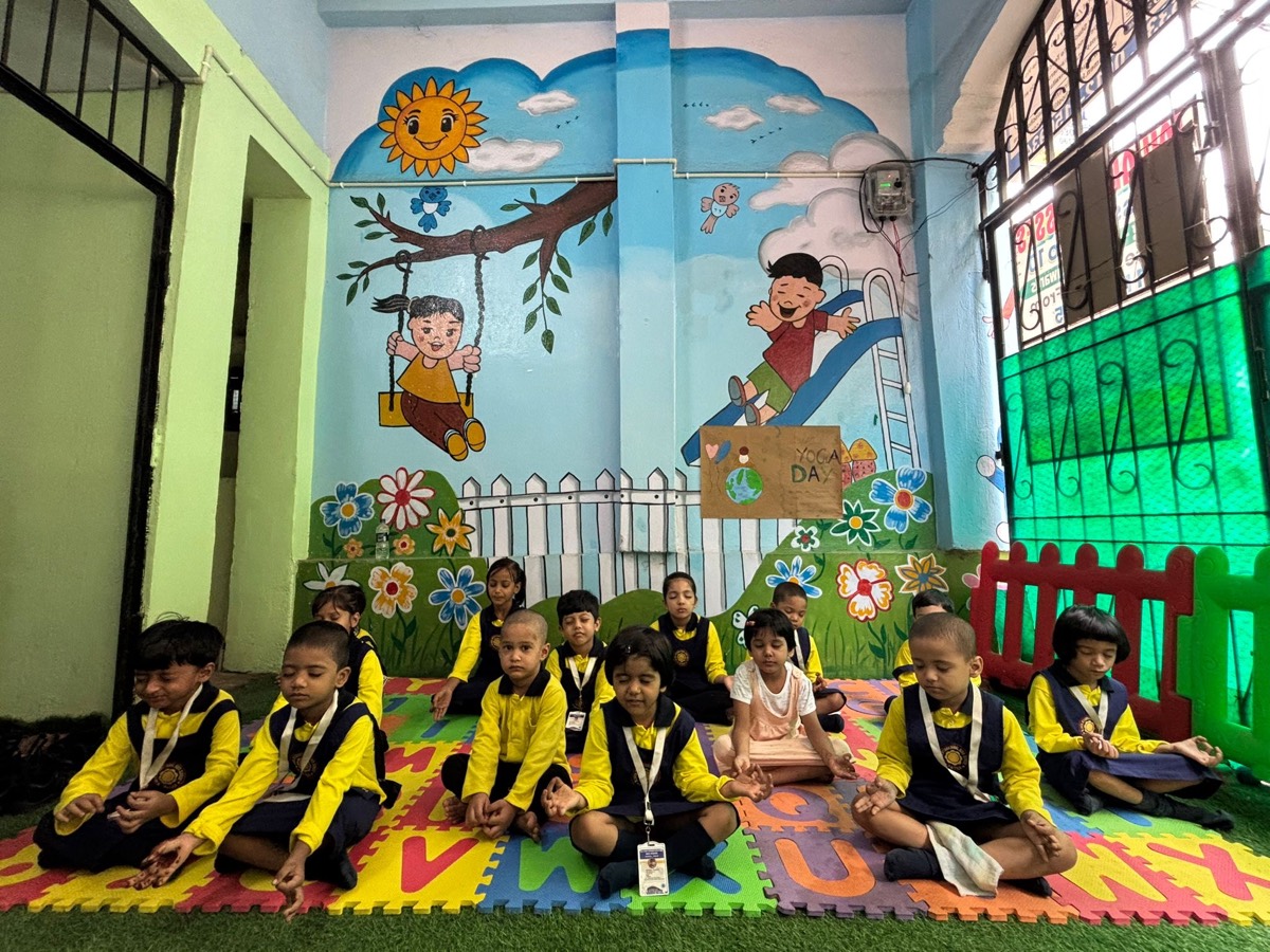 Children sitting cross-legged on floor mats for yoga in front of a painted mural